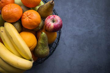 Variety of fruits such as apples, bananas, pears and oranges on a fruiterer on concrete background. Healthy food. Top view. Rigth side copy space.