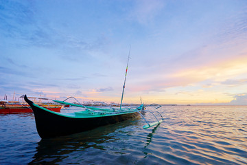 Beautiful colorful sunset on the seashore with fishing boats. Philippines, Siargao Island.