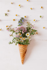waffle cone with a wild flowers on a white background. Creative design. Top view, flat lay.