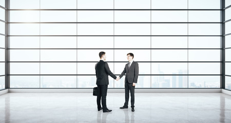 Businessmen shaking hands in modern interior