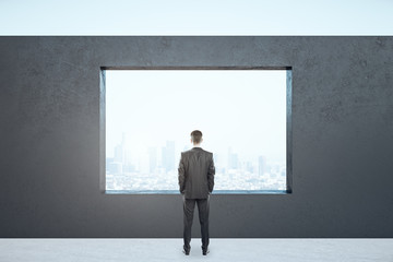 Obraz premium Businessman standing in empty interior with megapolis city view