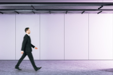 Fototapeta na wymiar Businessman walking in abstract purple interior room