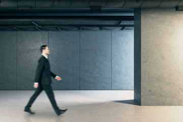 Businessman walking in urban concrete interior