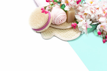Zero waste and eco friendly natural bathroom accessories, brush and glove with soap bar and spring pink flowers on white aqua mente background. Hygiene purity beauty care and spa. copy space. flat lay