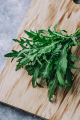 Arugula closeup. Green fresh garden herbs for culinary closeup on wooden table, top view. Arugula, parsley, dill, spinach, lettuce home planted overhead