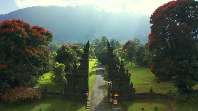 Ancient gate with pathway park garden in mountains at morning time. Landscape background of travel trip and holidays vacation in Handara, Bali, Indonesia. Aerial view 4K.