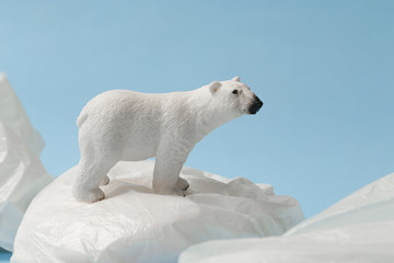 Plakat White polar bear on plastic bag on blue background, plastic pollution and climate change concept