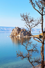 Baikal Lake on a sunny May day. A view of the natural landmark - Shamanka Rock from the coast of Olkhon Island. Beautiful spring landscape. Nature background