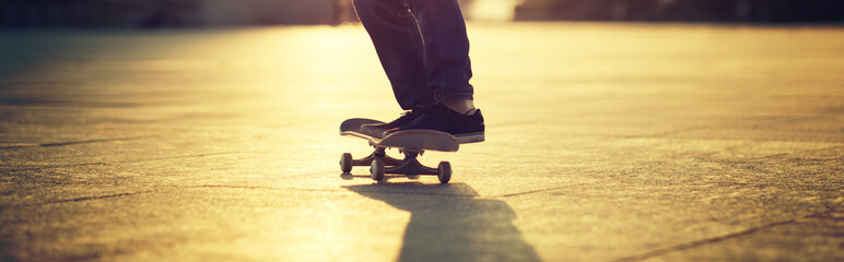 skateboarder legs riding skateboard on sunset city