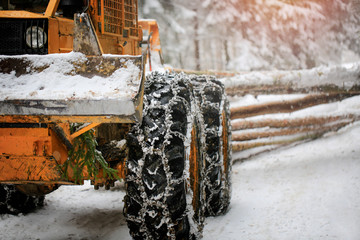 Logging machine giant wheels equipped with snow chains. In the winter Slovak country. He works in...