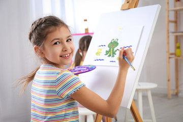 Cute little child painting during lesson in room