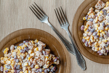 salad of red and white beans and sweet corn on glass plates close up