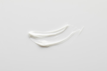 Top view of cosmetic cream brushstrokes on grey background