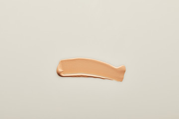 Top view of tone cream brushstroke on grey background