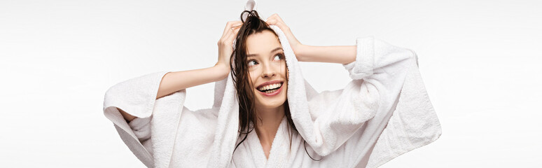 panoramic shot of happy girl wiping wet clean hair with white terry towel while looking away isolated on white