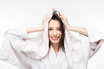 happy girl wiping wet clean hair with white terry towel while smiling at camera isolated on white