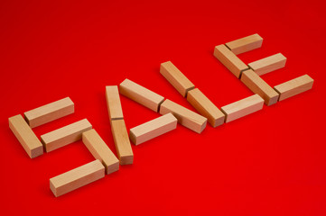 Sale inscription made up of wooden blocks on a red background. Background for shops and commerce.