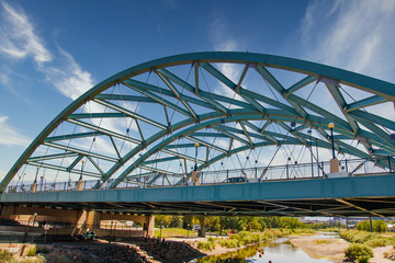 An old green metal bridge over a river in Denver, Colorado