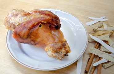 Dry baked leg pork without fat in white dish and Chinese herb on brown wooden table
