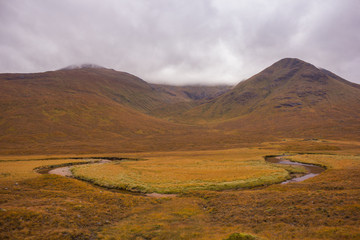 meander landscape of a river in a valley with autumnal vegetation between mountains, cold and cloudy day