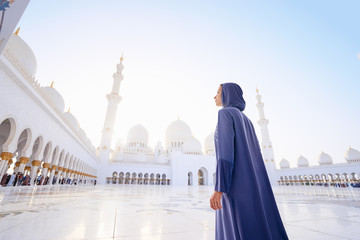 Traveling by Unated Arabic Emirates. Woman in traditional abaya standing in the Sheikh Zayed Grand...
