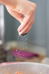 Closeup mid section of a chef putting salt in the kitchen