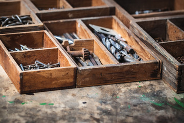 Toolbox with nails, screws and drill bit on wood table