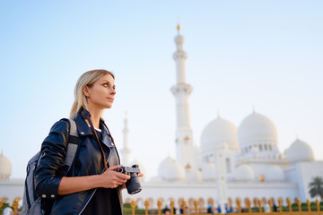 Traveling by Unated Arabic Emirates. Pretty Young Woman with camera standing near the Sheikh Zayed...