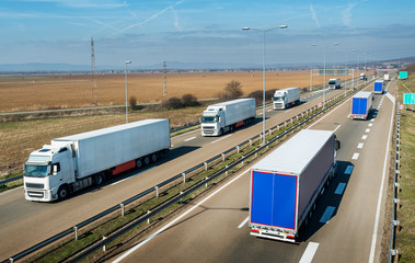 Convoys of transportation trucks passing on a highway on a bright blue day. Highway transportation...
