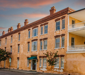 An old peach colored stucco building with veranda under nice sky