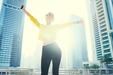 Having good mood. Enjoying the sound. Happy young woman with earphones listening music on...