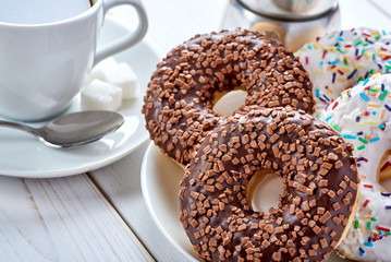 Top Closeup photo of sweet breakfast or snacks. Chocolate and vanilla donuts and cup of black coffee