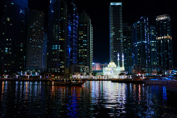 Fototapeta na wymiar Big city lights. Night cityscape of Dubai marina embankment with skyscraper.