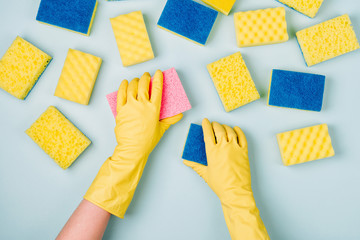 Female hands cleaning with sponge on blue background. Cleaning or housekeeping concept background. Copy space. Flat lay, Top view. - obrazy, fototapety, plakaty