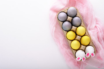 yellow and blue Easter eggs, Easter Bunny in cardboard box on pink fabric on white background