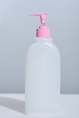 white plastic bottle with dispenser and pink lid on white background with shadow