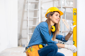 Attractive young female builder checking level - 327535036