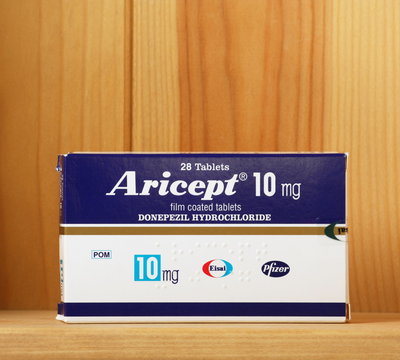 Bracknell, England, UK - March 04, 2014: A box of the drug Aricept on a wooden shelf. Aricept is produced by pharmaceutical company Pfizer for the treatment Alzheimer's disease.