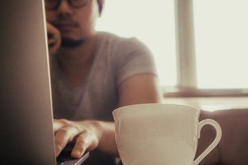 White cup of hot coffee on the table of a freelance man.