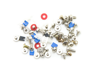 Small bolts, screws and nuts are scattered interspersed with red washers and jumpers in blue and black for the computer. Fasteners for electronics assembly. White isolated background. Close-up.