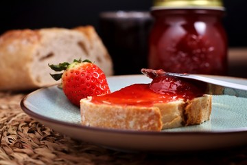 Close-up view of knife spreading jam on slice of bread
