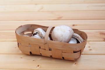 fresh mushrooms in a wicker basket on a wooden floor