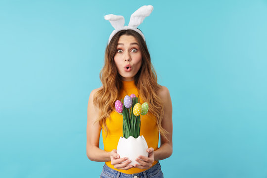 Portrait of young woman wearing bunny ears holding painted easter eggs
