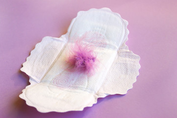 Menstrual pads and tampons on menstruation period calendar with on lilac background.