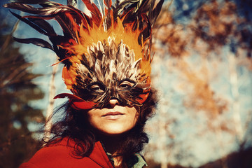 Young woman with a colorful feather face mask.