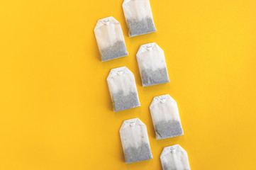 A lot of disposable tea bags on a yellow background.