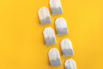 A lot of disposable tea bags on a yellow background.