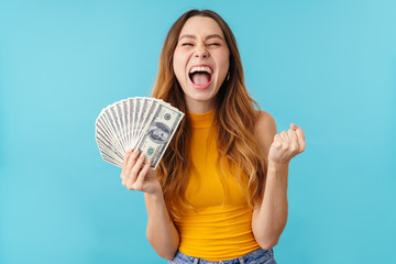 Portrait of joyous caucasian woman laughing and holding dollar banknotes