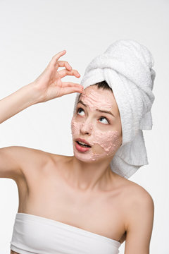 dissatisfied girl removing scrab mask from face while looking at camera isolated on white