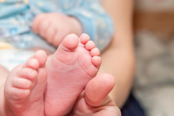 Mom holds her newborn baby's feet in her hands.